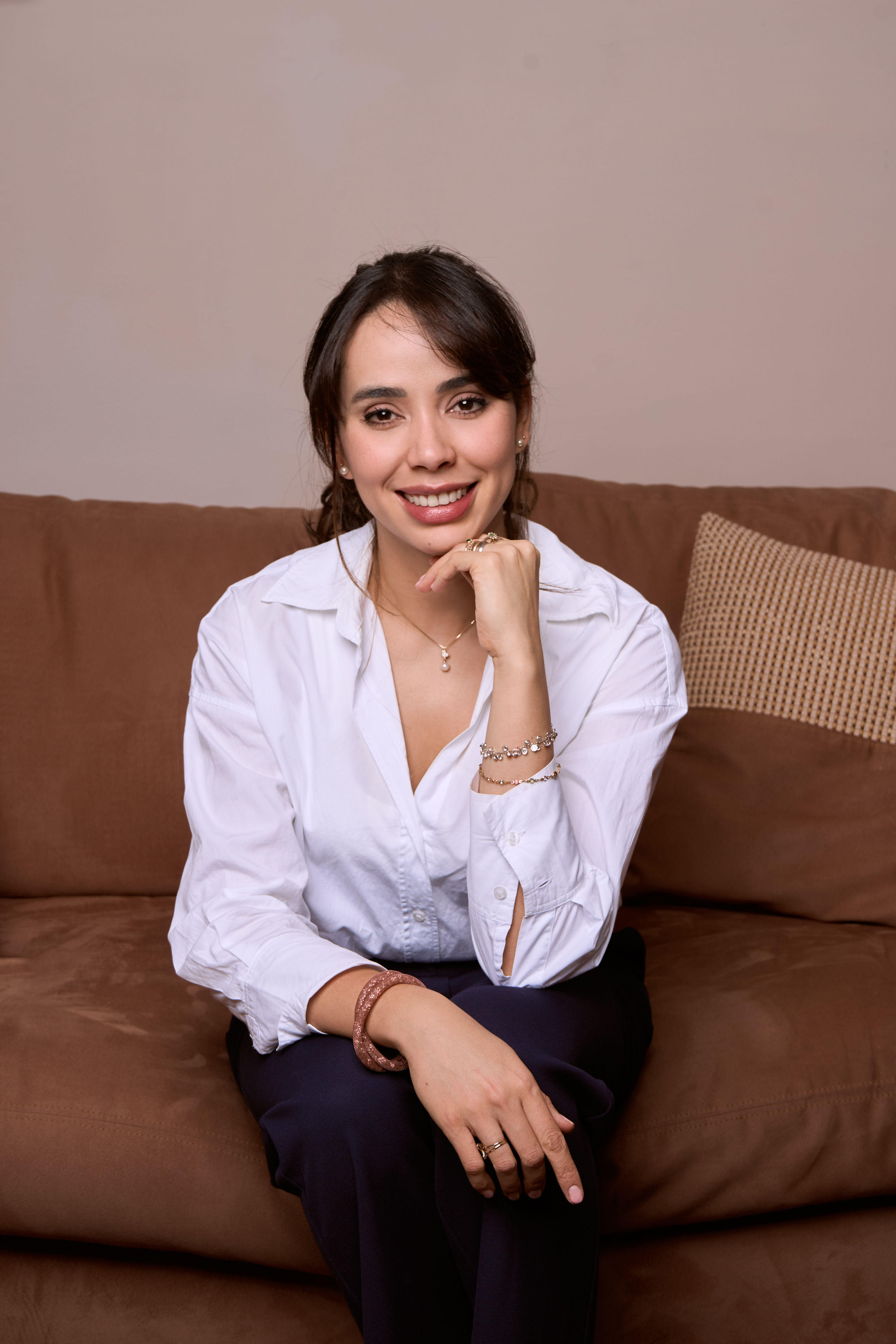 Amanda Aires sonriendo, sentada en un sofá